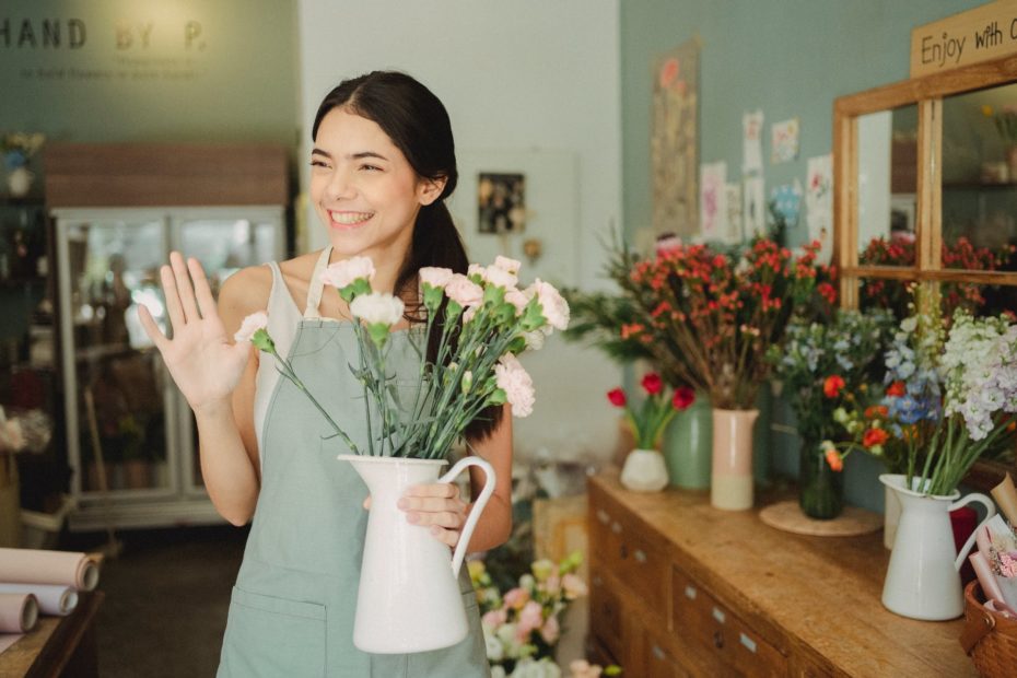 woman holding vase with flowers in shop